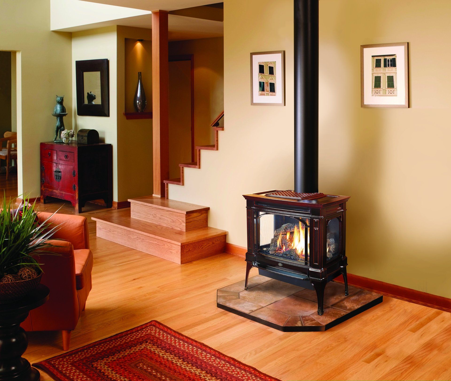 Wood-burning stove in a living room with wooden floors, stairs, and beige walls.