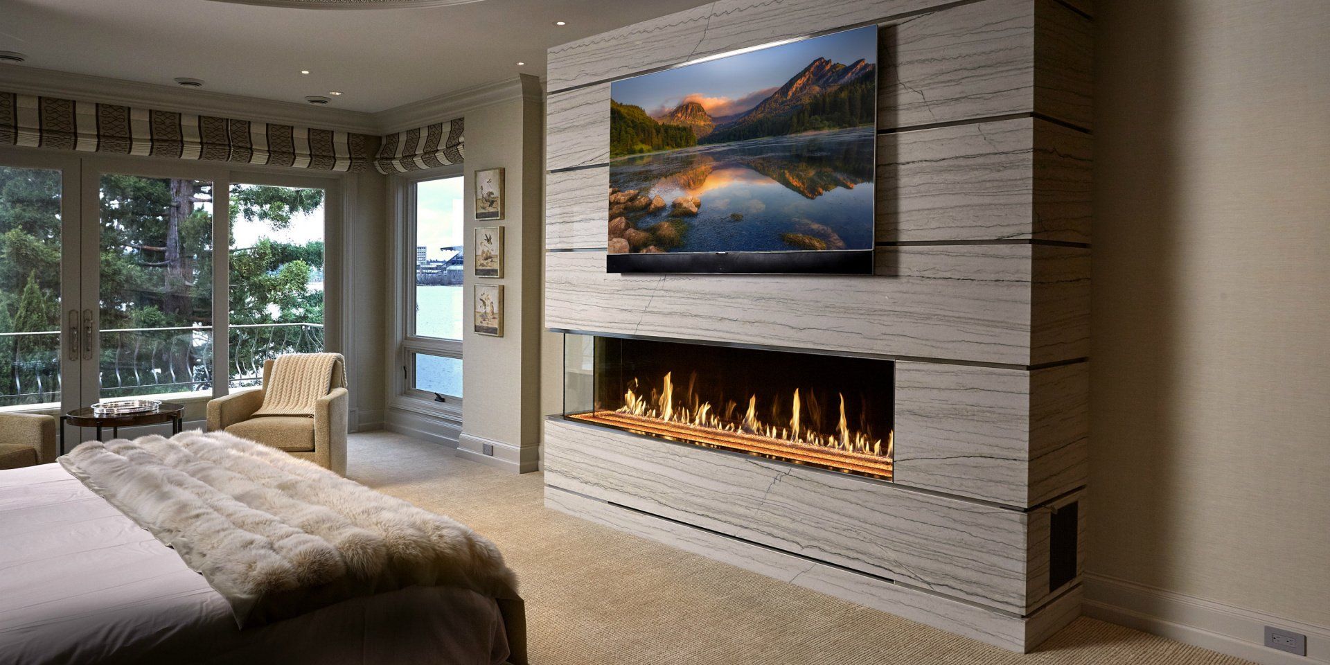 A luxurious bedroom with a fireplace and large picture window overlooking a scenic view.