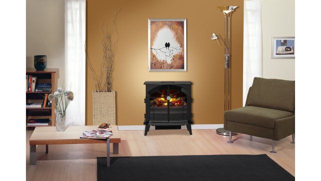 Living room with an electric fireplace, artwork, and furniture, against a golden-brown wall.