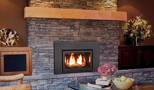 Fireplace with flames, set in a stone wall. A wooden mantel and surrounding furniture are visible.