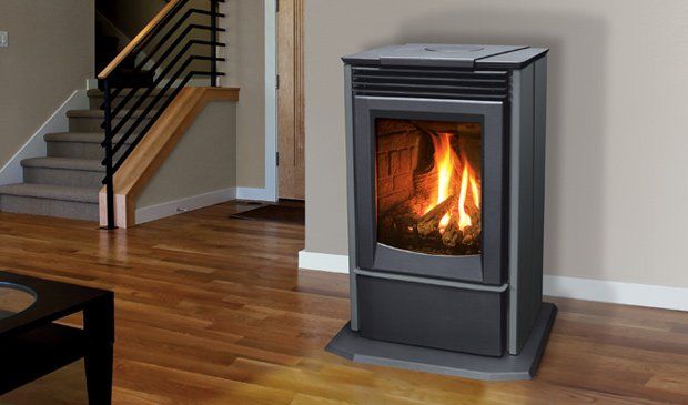 Gray pellet stove with lit flames in a living room, near stairs and a wooden floor.