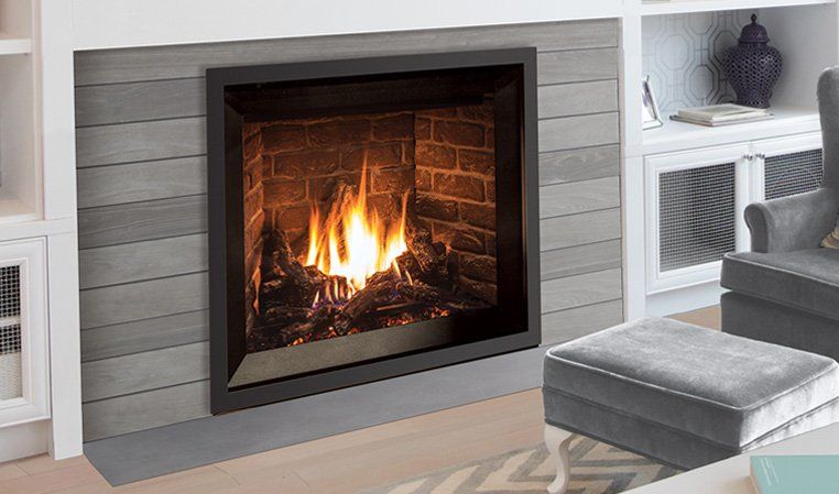 Fireplace with burning flames inside a black frame, set in a gray paneled wall.