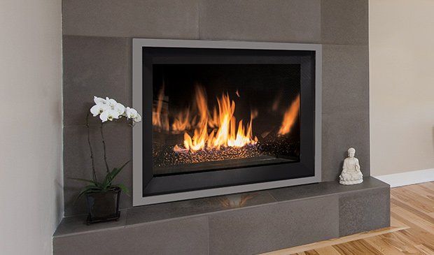 Gas fireplace with flames, gray tile surround, and flowers.