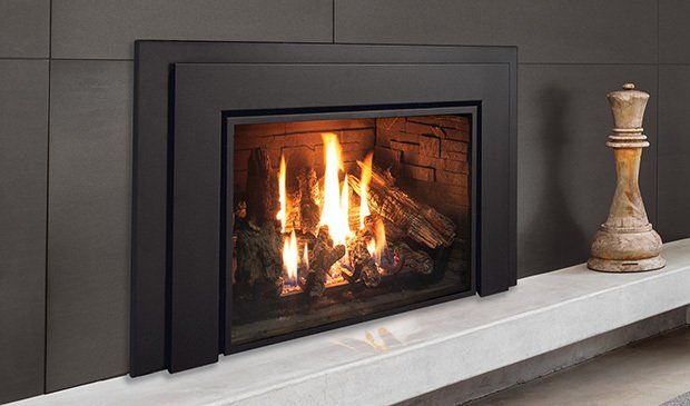 A modern gas fireplace with a black surround and burning flames, sitting on a gray mantel.