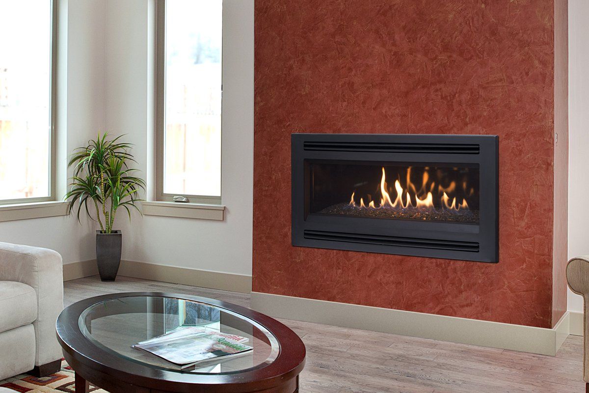 Fireplace with flames in a living room; brown textured wall, windows, and oval coffee table.