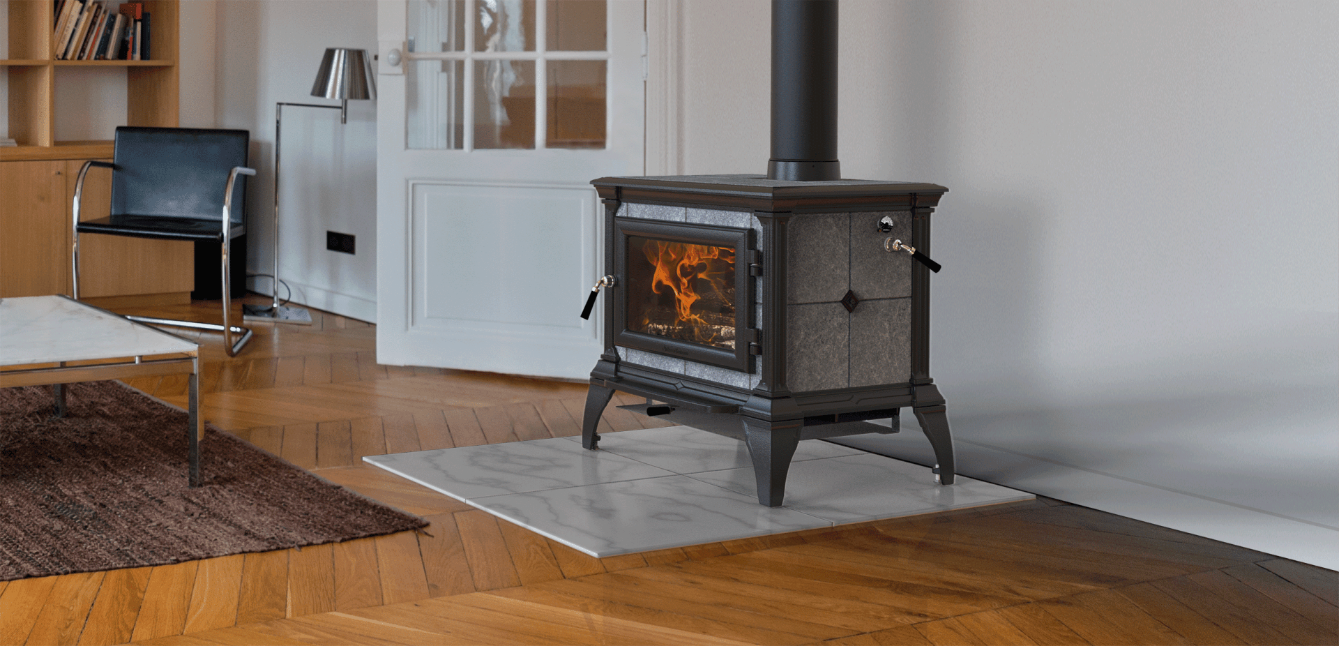 A wood-burning stove with a lit fire sits on a light-colored floor, a rug is in the foreground.