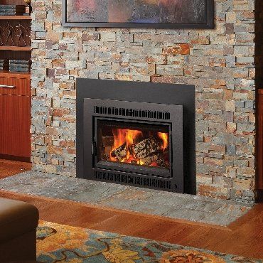 Gas fireplace with flames, set into a stone wall, in a living room.
