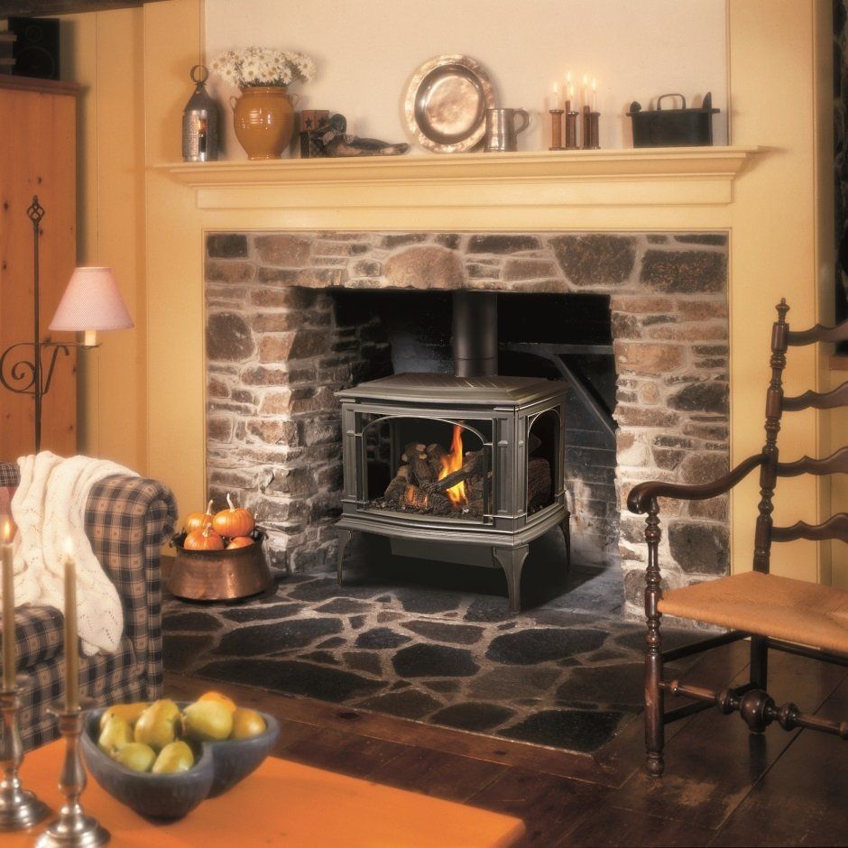 Fireplace with wood-burning stove, stone surround, mantel with decor, and cozy living room furniture.