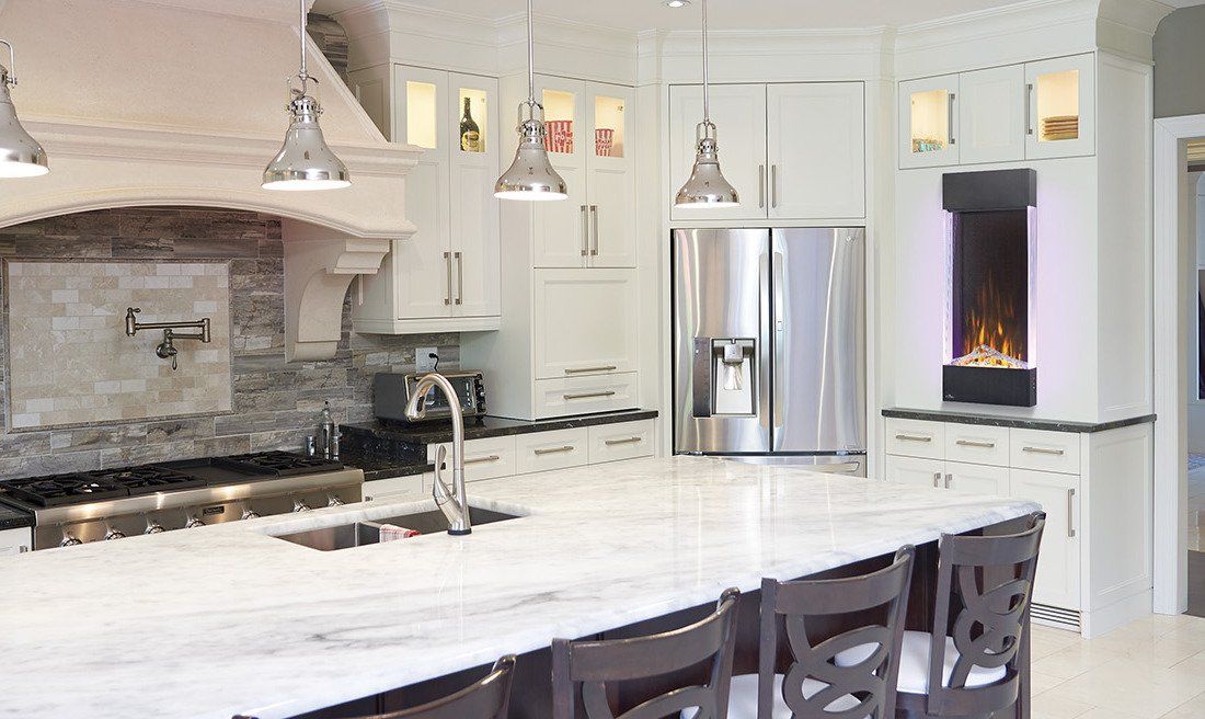 Spacious white kitchen with island, stainless steel appliances, and a modern fireplace.