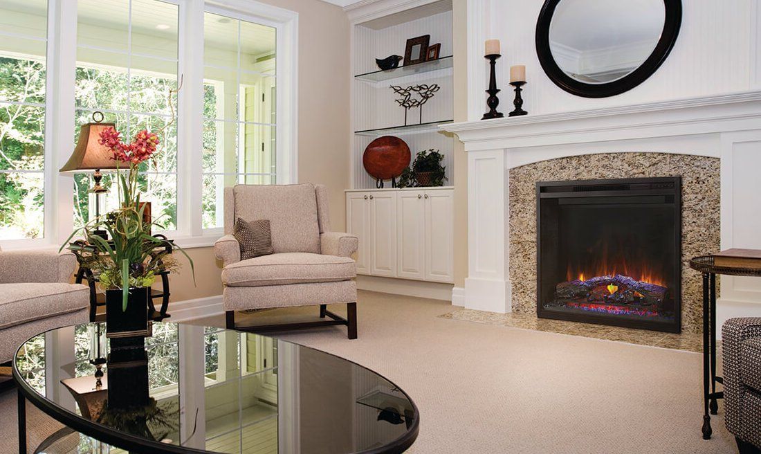 Cozy living room with fireplace, beige carpet, armchair, black coffee table, and large windows.