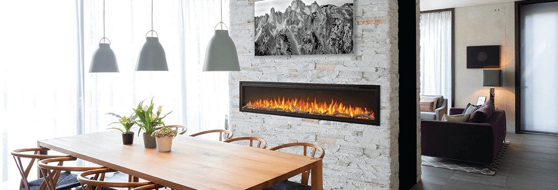 Dining room with a fireplace, long wooden table, and hanging lights.