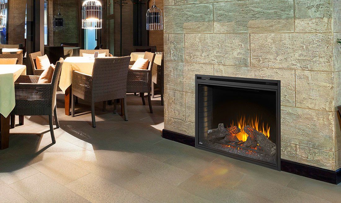 Fireplace built into stone wall in a restaurant, with tables and chairs visible.