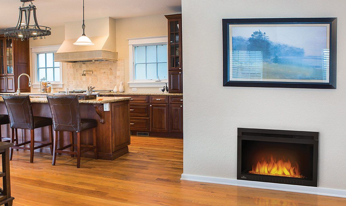 A modern electric fireplace with a flame effect, mounted on a white wall in a kitchen.