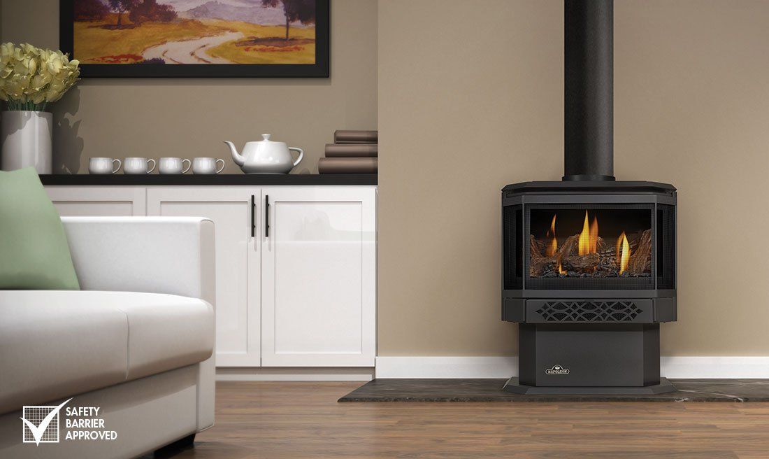 Gas fireplace against a beige wall, black pipe, lit flames, black base, living room setting.