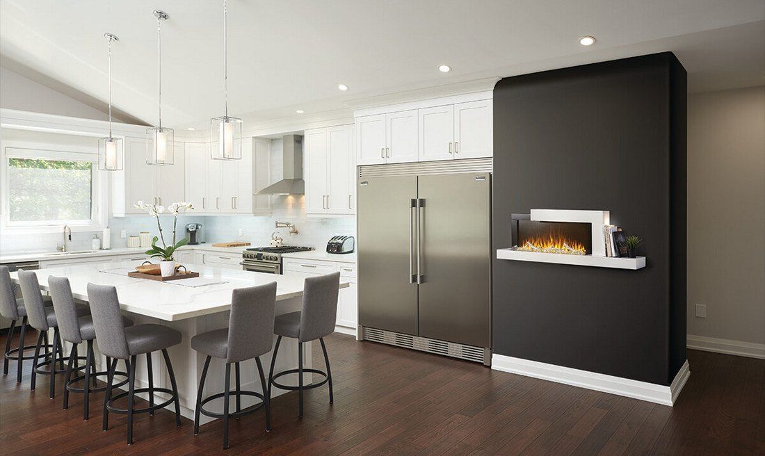 Modern kitchen with large island, stainless steel fridge, and black fireplace wall.