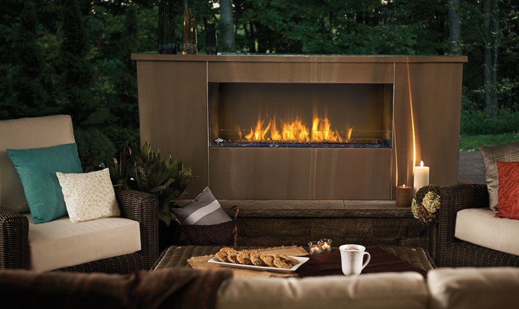 Outdoor fireplace with flames, seating area, and table with snacks.