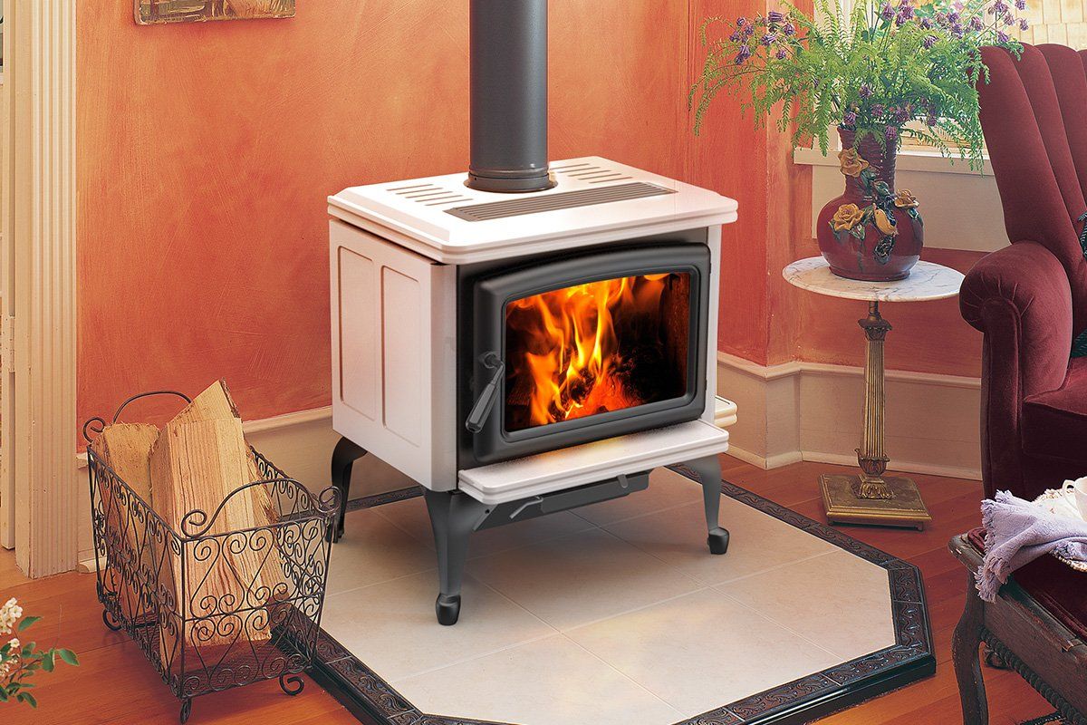 White wood stove with burning fire, black chimney, and log holder on a rug.