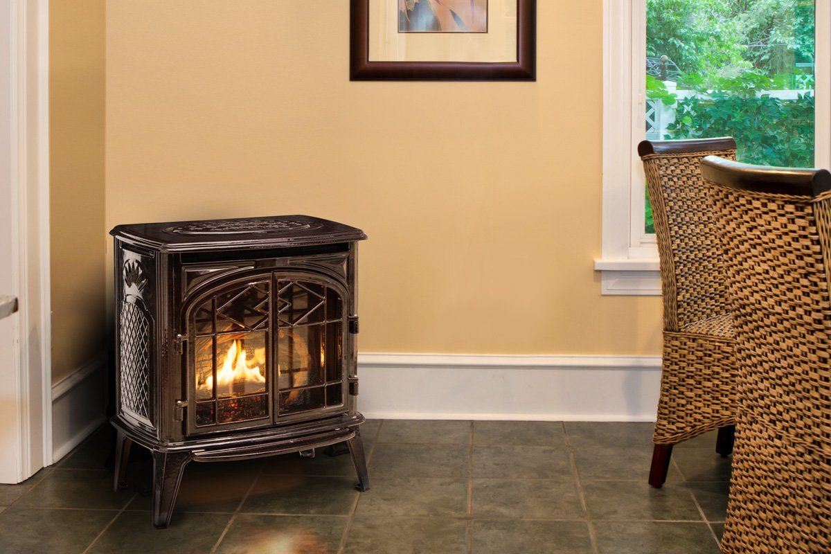 Gas fireplace in a room with yellow walls, dark floor, and wicker chairs.