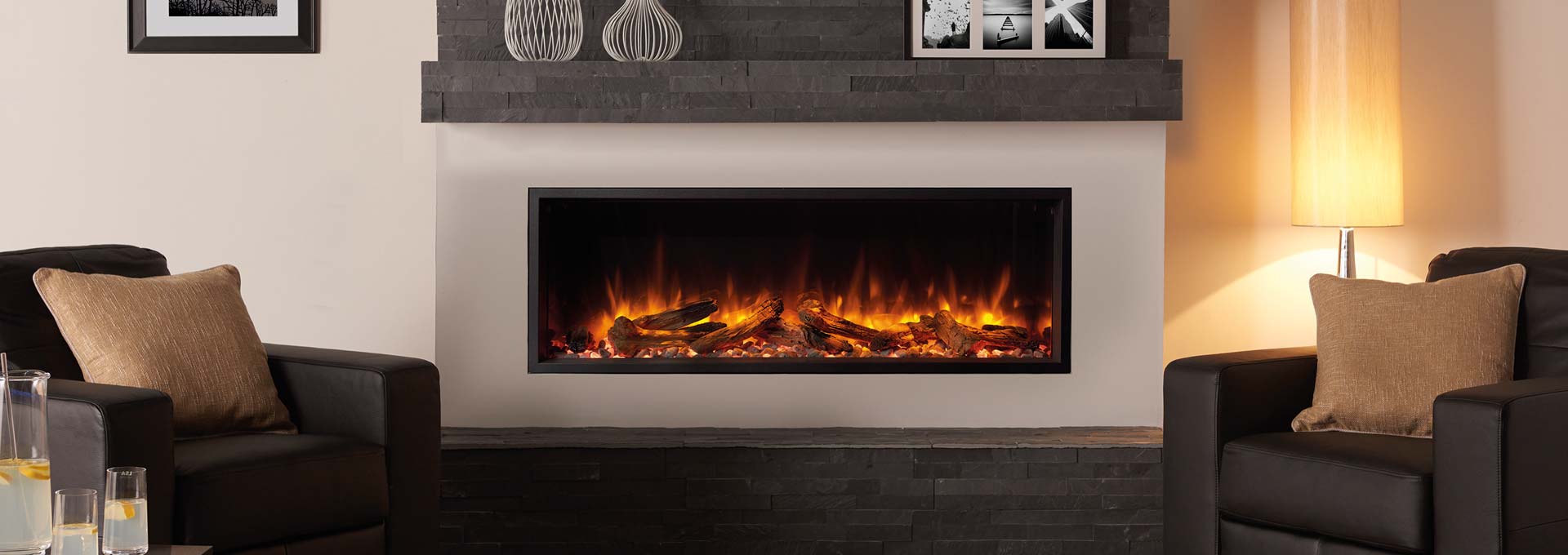 A fireplace with glowing flames in a modern living room setting, flanked by two chairs.