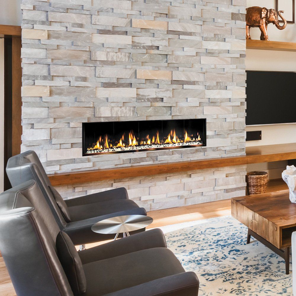 Modern living room with stone fireplace, chairs, and wood accents. Fire flames visible.