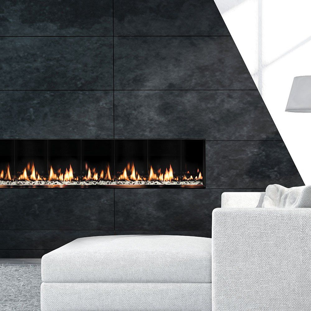Modern fireplace with flames in a dark stone wall; white sofa in foreground.