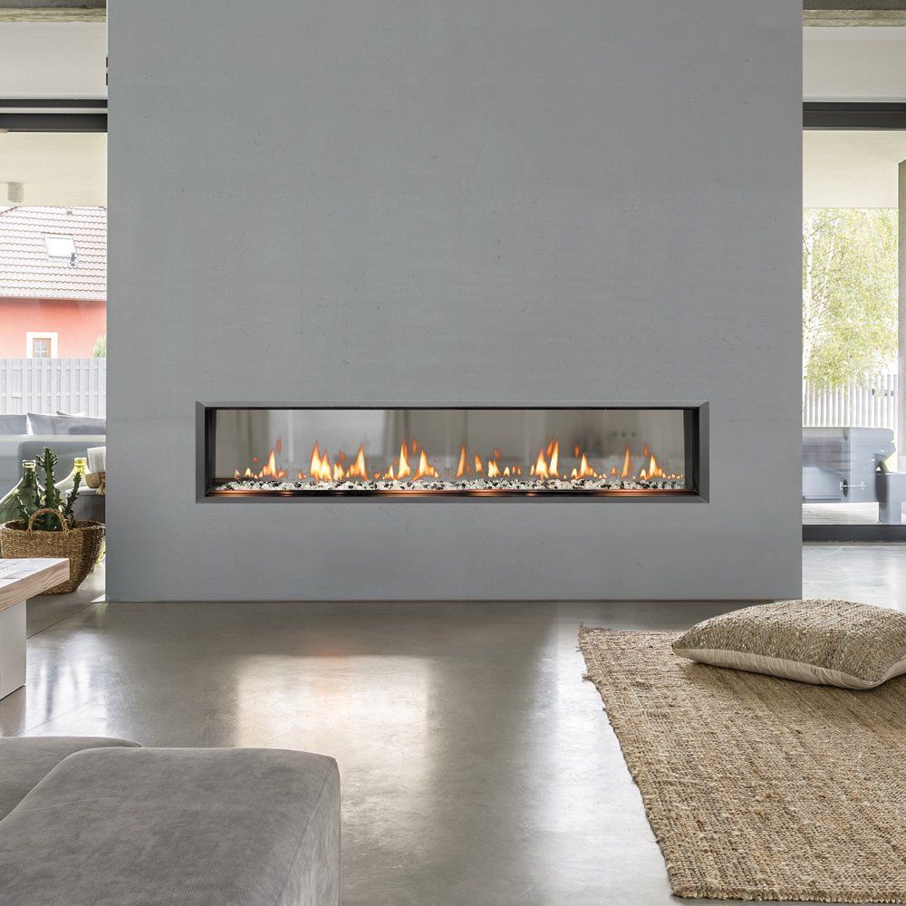Modern living room with fireplace built into gray wall; rug and floor pillow in foreground.