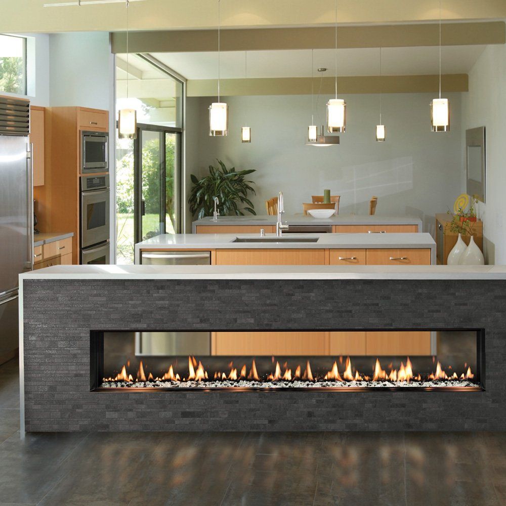 Modern kitchen island with a built-in linear fireplace; light wood cabinets, gray tile, and pendant lights.
