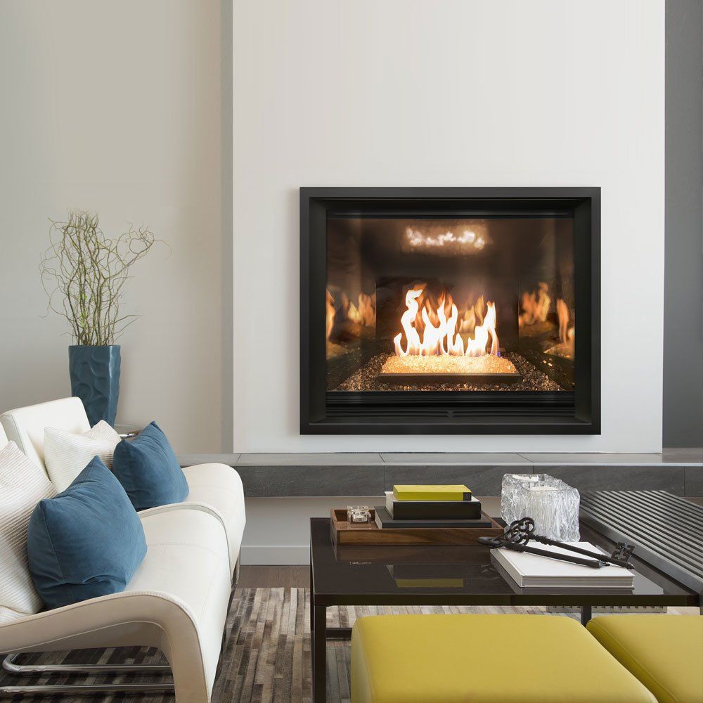 Living room with a lit fireplace, white sofa, blue pillows, coffee table, and yellow ottomans.