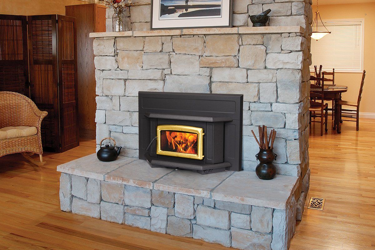 Fireplace with stone facade and burning fire in a room with hardwood floors.