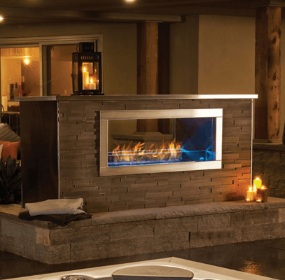 Outdoor fireplace with flames, stone facade, stainless steel trim, lantern, and seating area.