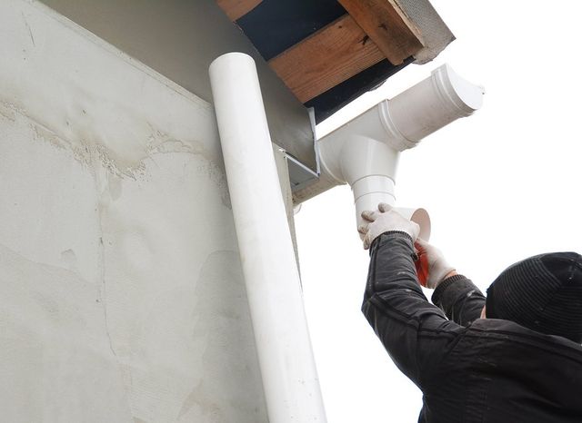 worker replacing gutter pipe
