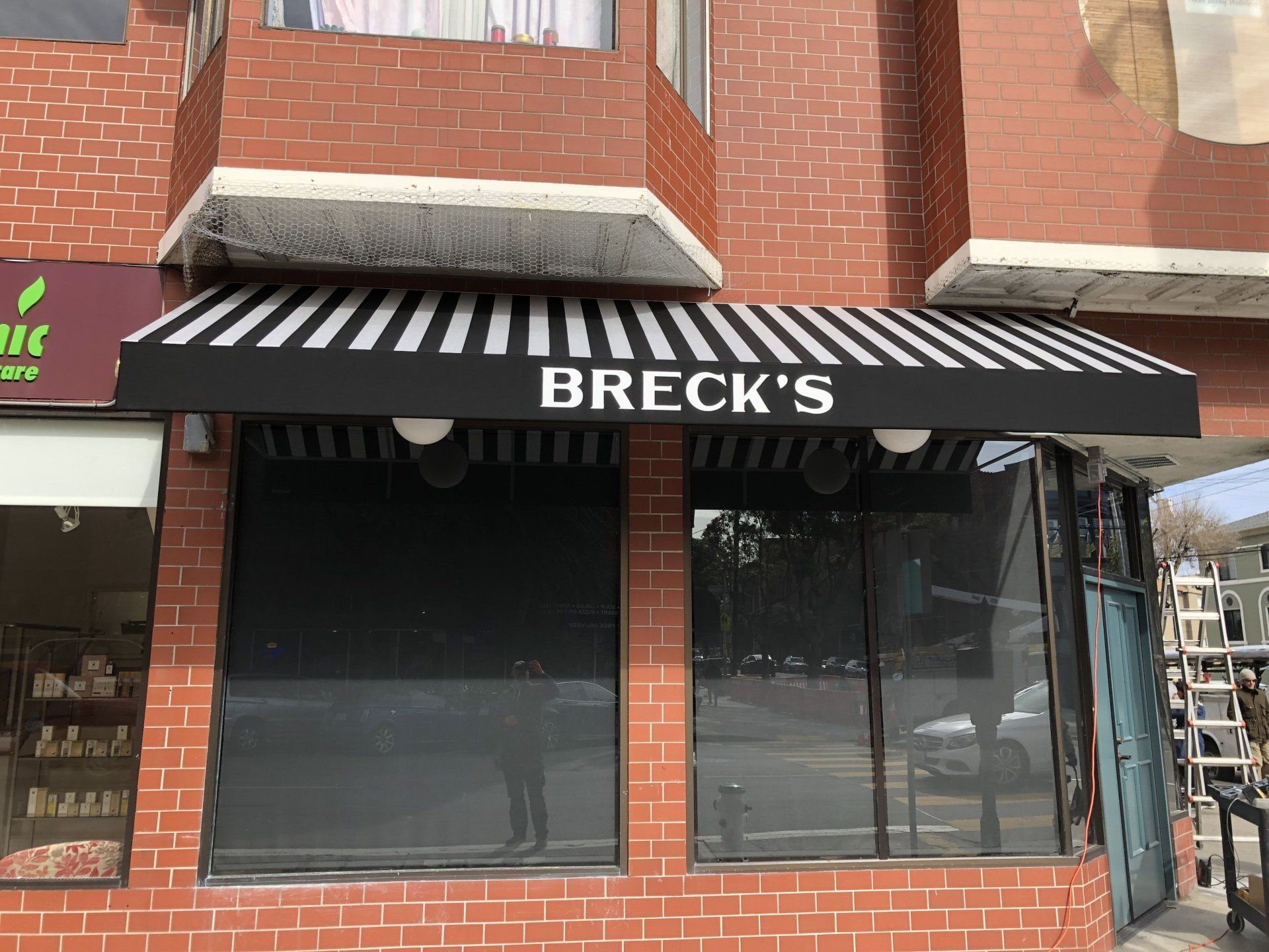 A black and white awning is on the side of a brick building.