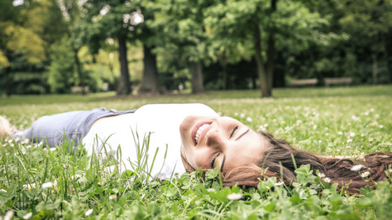 A happy woman lying in the grass and smiling 