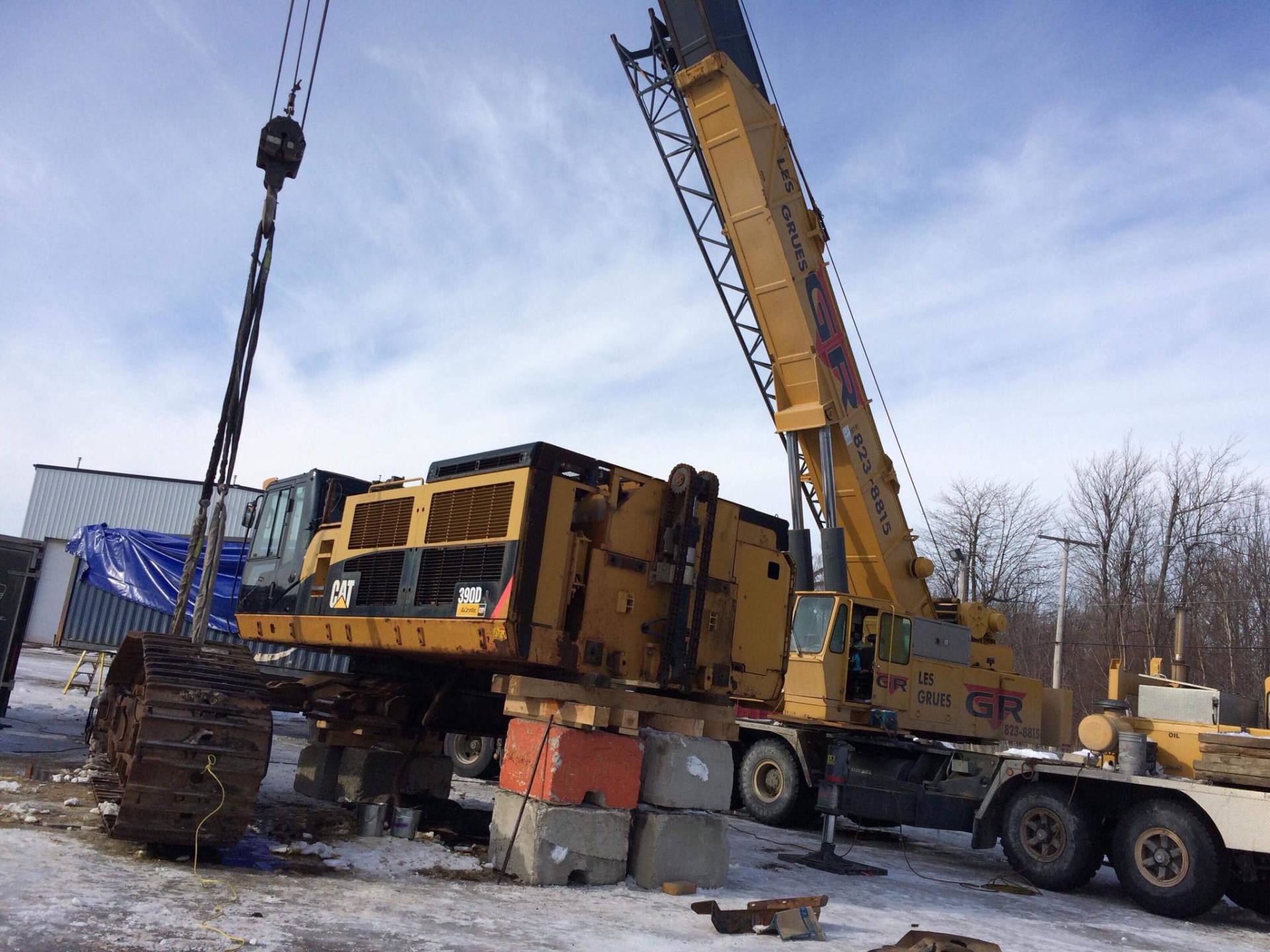 Grue jaune soulevant du matériel sur un chantier de construction sur un sol enneigé
