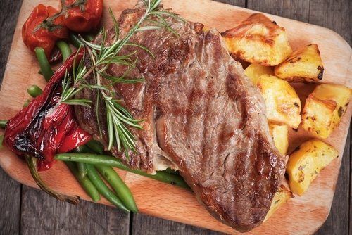 un tagliere con una bistecca e delle patate al forno