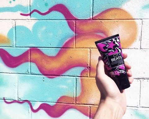 Murales con dei capelli e davanti una mano con in mano una crema
