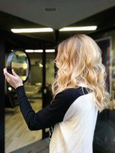 ragazza con capelli biondi mossi che si guarda allo specchio