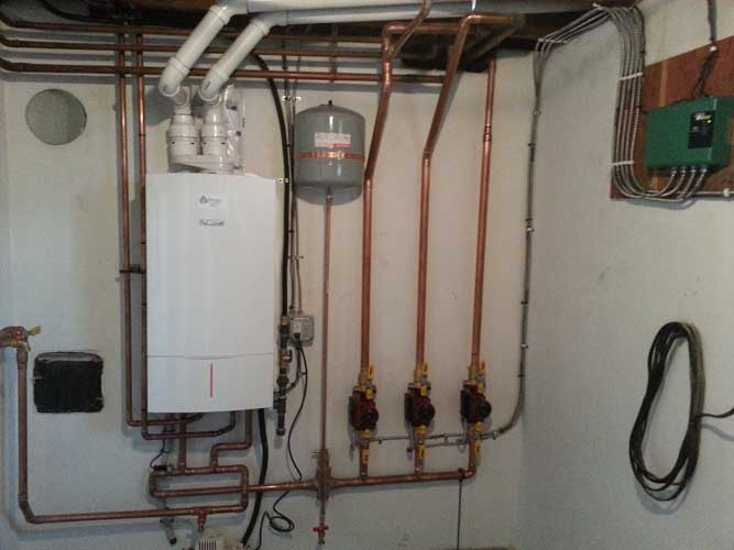 A room with a boiler and copper pipes on the wall