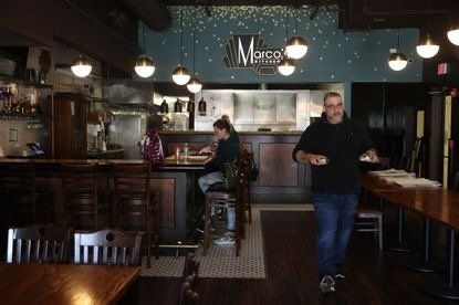 A man is standing in a restaurant with a sign that says marco