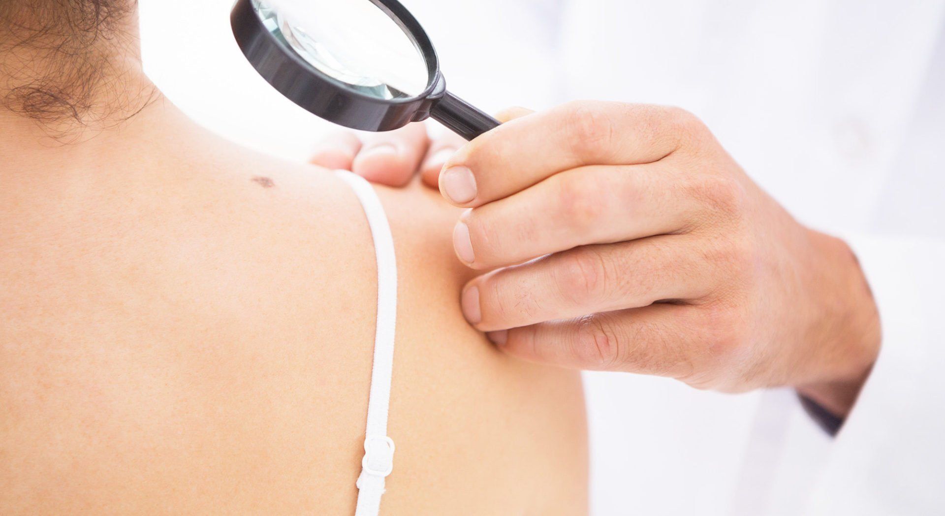 Un médico está examinando la piel de una mujer con una lupa.