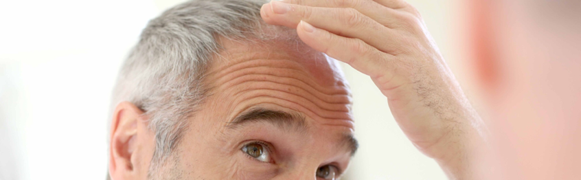 Un hombre se mira el cabello en el espejo.