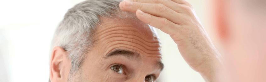 Un hombre se mira el cabello en el espejo.