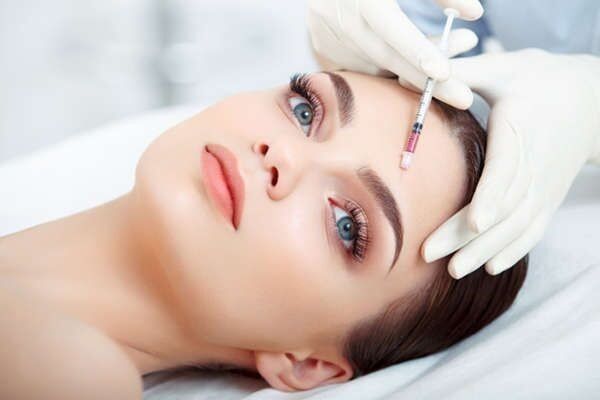 Una mujer recibe una inyección de botox en la frente.
