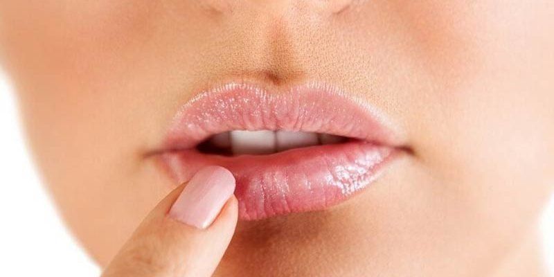 Un primer plano de los labios de una mujer con su mano sobre ellos.