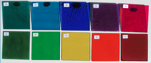 A bunch of different colored sheets of glass are lined up on a table.