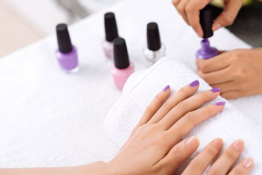 applicazione smalto viola su una mano