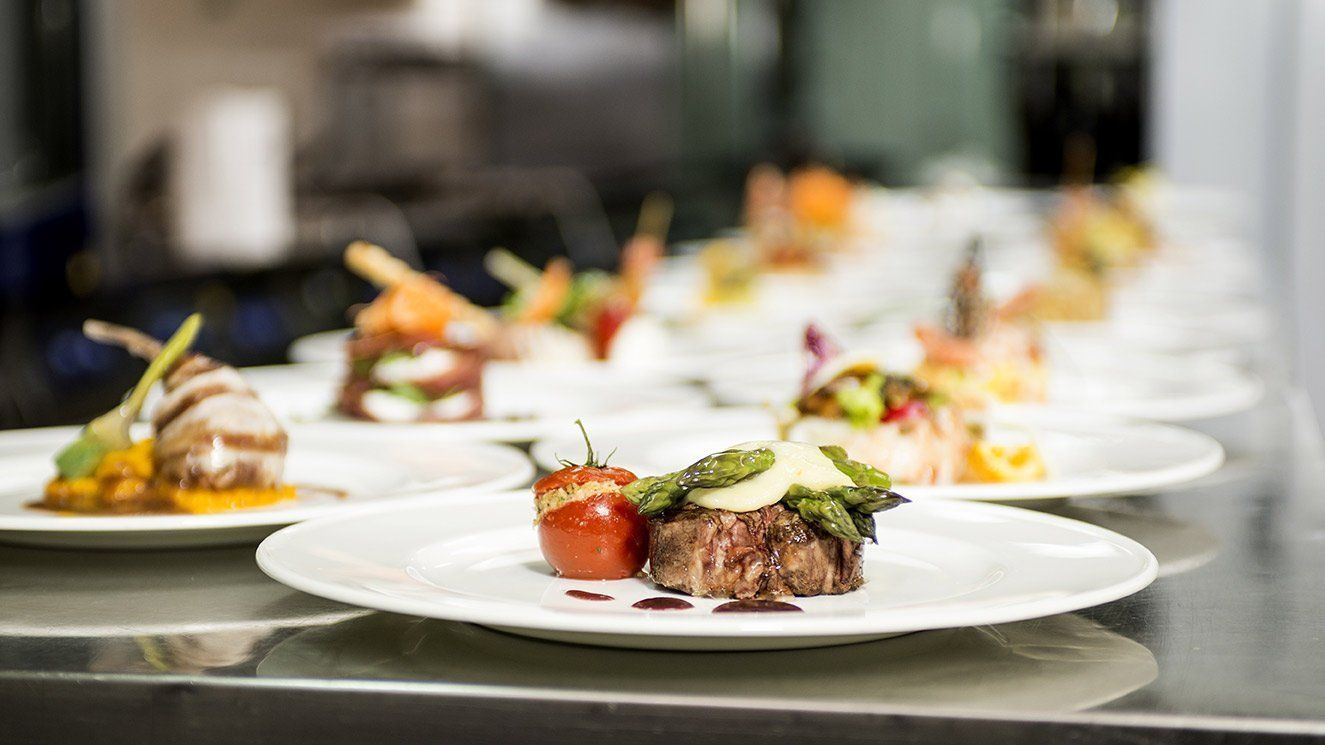 A row of plates of food on a counter in a kitchen.