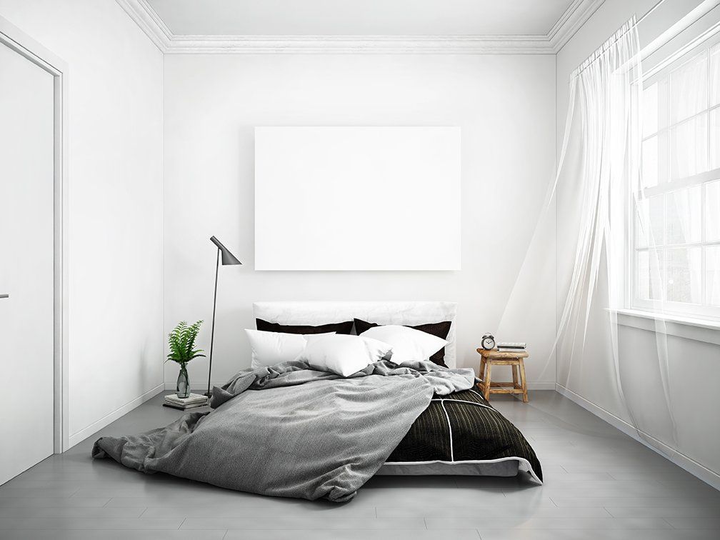 Um quarto com uma cama, um candeeiro, um quadro na parede e uma janela.