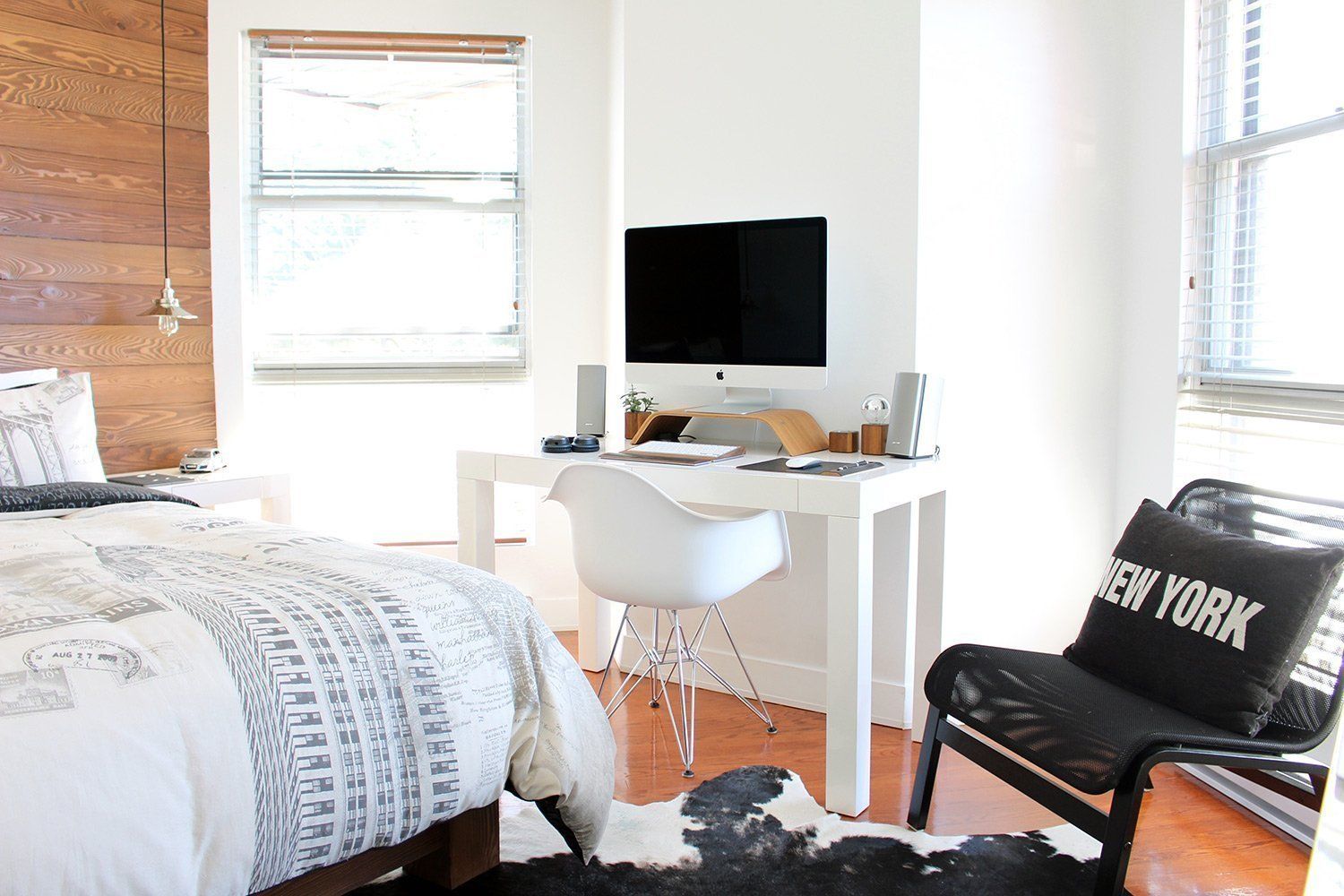 Um quarto com cama, escrivaninha, cadeira e um travesseiro que diz Nova York