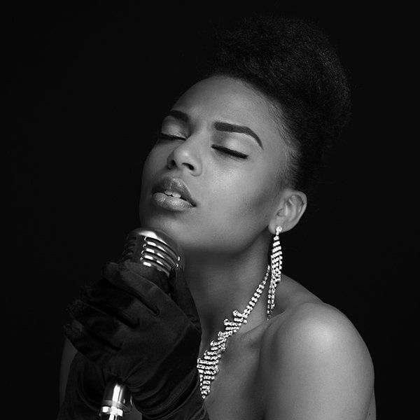 A black and white photo of a woman singing into a microphone